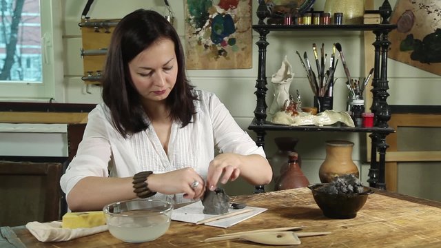 Fast motion video shot of an artisan woman modeling a clay sculpture in a studio
