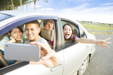 young  people enjoying road trip in the car and making selfie