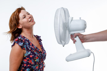 Middle-aged woman cools down with an electric fan