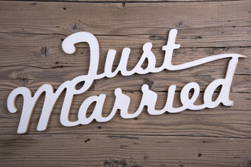 Word JUST MARRIED on old wooden background