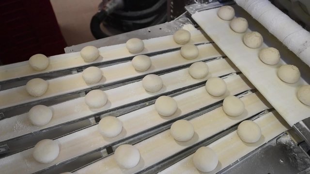 Br&ouml;tchen auf dem Fliessband einer Gro&szlig;b&auml;ckerei- industrielle Herstellung von Tiefk&uuml;hlbackwaren