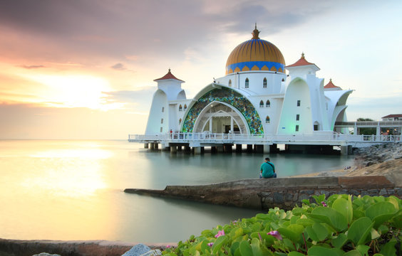 Man looking at the Majestic view of Malacca Straits Mosque during sunset.