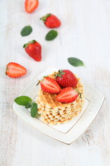 Waffles with strawberries on a wooden table