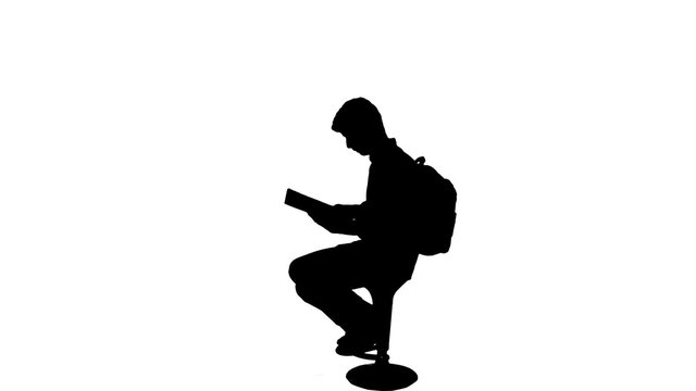 University student studying silhouette - 1080p. Silhouette of a sit down reading book studying for exams. Full HD
