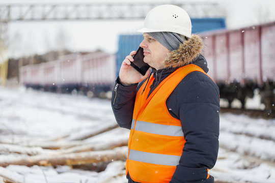 Engineer talking on the smartphone near the freight wagons