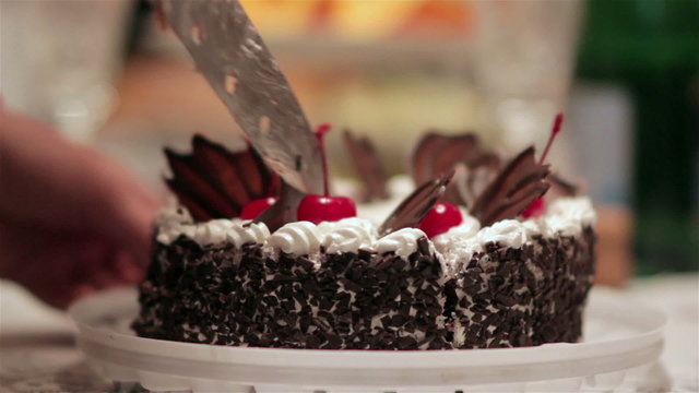 cutting cake with cherries/chocolate cake with cherries cut into pieces