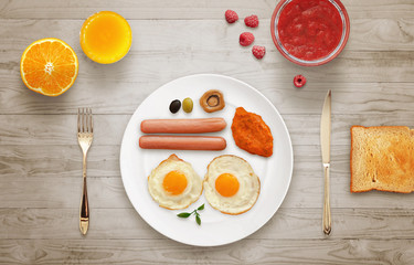 Breakfast with egg, hot dog, mushroom, chutney sauce, tomato, olive. Jar of jam, raspberry, strawberry, orange, juice, toast, tablecloth, wooden table