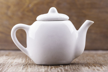 small white ceramic teapot on a wooden surface closeup