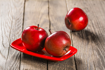 Three red apple on red ceramic plate