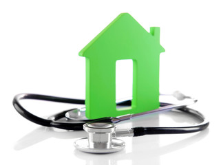 Concept of family medicine - green house and stethoscope isolated on white background