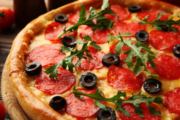 Tasty pizza with salami on decorated wooden table