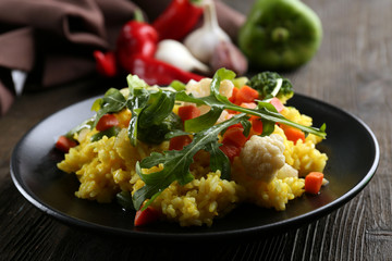 Black plate with vegetable risotto on served wooden table