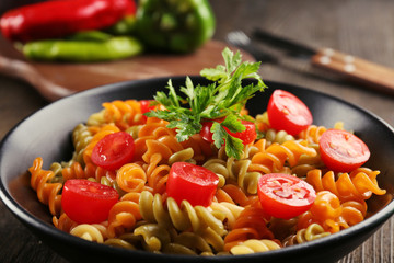 Delicious macaroni dish in black bowl on served wooden table