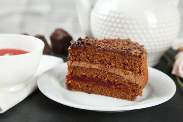 Sliced chocolate cake on plate, on wooden table  background