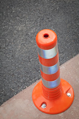 closeup orange bollard on pavement