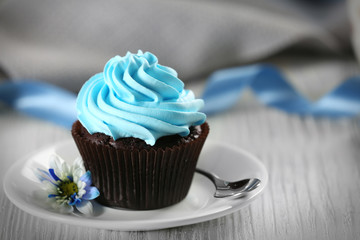 Delicious chocolate cupcake with blue cream on decorated wooden  table, close up