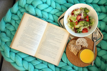 Open book, plaid and juice on sofa