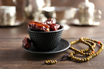Dates fruit and rosary on served wooden background, close up