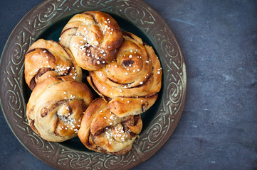 Traditional Swedish cinnamon buns served on a rustic plate. A very popular snack throughout Scandinavia known as Fika when taken with a cup of coffee.