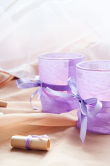 Fototapeta na wymiar Two aromatic candles in glass candlesticks with lavender paper on table close up