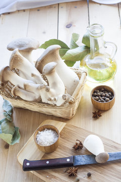 Basket with mushrooms, olive oil and ingredients for cooking on the wooden table of the kitchen background