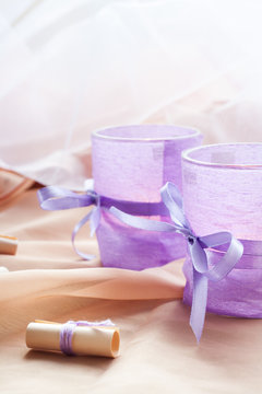 Two aromatic candles in glass candlesticks with lavender paper on table close up