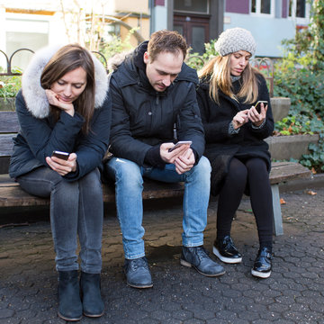 Drei Freunde am Smartphone drau&szlig;en im Winter