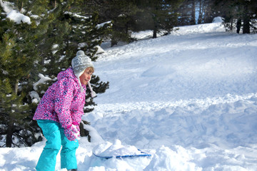 Fototapeta na wymiar Happy snowy holidays. Picture of a little girl playing with snow in a mountain forest