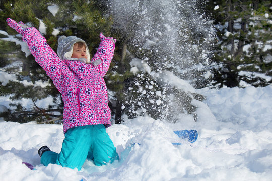 Happy snowy holidays. Picture of a little girl playing with snow in a mountain forest