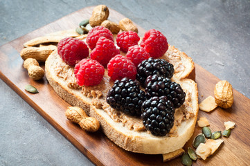 Healthy snack of sliced sourdough bread topped with peanut butter and fresh blackberries and...