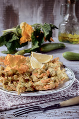 Homemade Zucchini Pancake on a plate, accompanied by zucchini and zucchini flowers.
