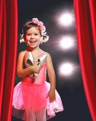 Fototapeta premium little girl ballerina ballet dancer on stage in red side scenes