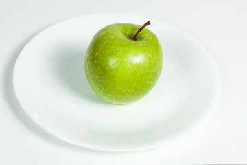 Green Apple with water drops in a plate