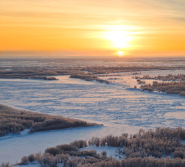 Fototapeta na wymiar Forest river during cold winter sundown, top view