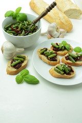 Bruschettas with dried tomatos, green bean, olive and garlic