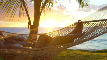 Romantic couple relaxing in tropical hammock at sunset. Summer Luxury Vacation. SLOW MOTION.  - Powered by Adobe