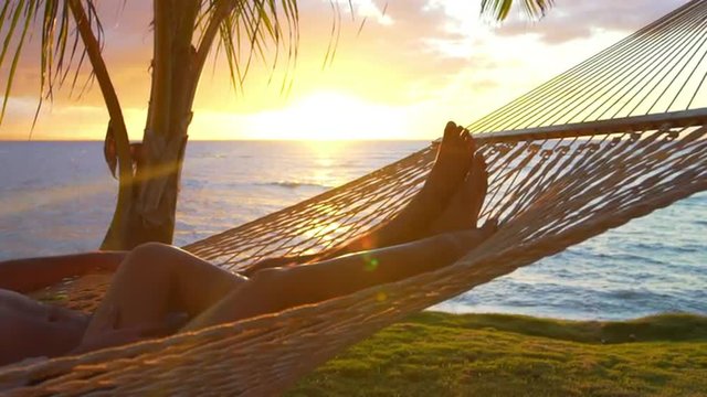 Romantic couple relaxing in tropical hammock at sunset. Summer Luxury Vacation. SLOW MOTION. 