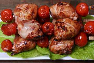 grilled barbecue kebab chicken legs and tomatoes on skewers