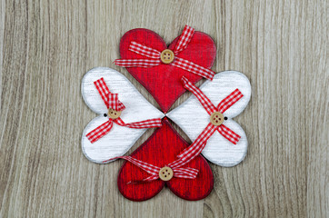 Wooden background with red and white hearts  in the form of clover sheet