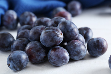 Fresh plums on the white wooden background