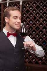 Attractive male waiter is smelling pretty drink