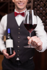 Cheerful young sommelier is serving a customer