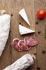 Traditional sliced salami on wooden board with brie Camembert