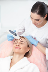 Cheerful young cosmetologist is undergoing cavitation treatment