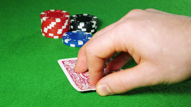 Poker player with pocket pair of jacks looks at his cards.