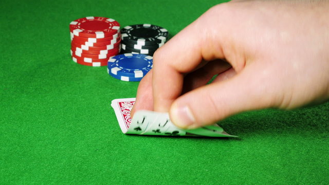 Poker player with pocket pair of jacks looks at his cards.