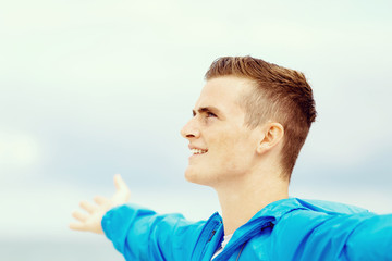 Young man in sport wear with outstretched arms