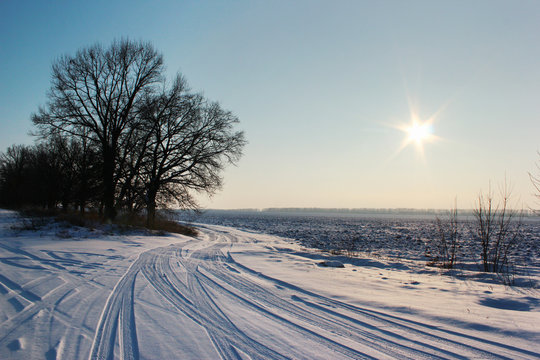 Sun over ploughed field covered with snow. Winter rural landscape