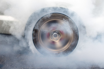 race car burns rubber off its tires in preparation for the race