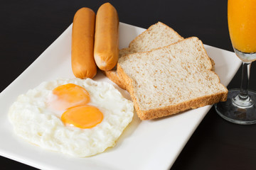 Fried eggs with sausages and bread on the white plate